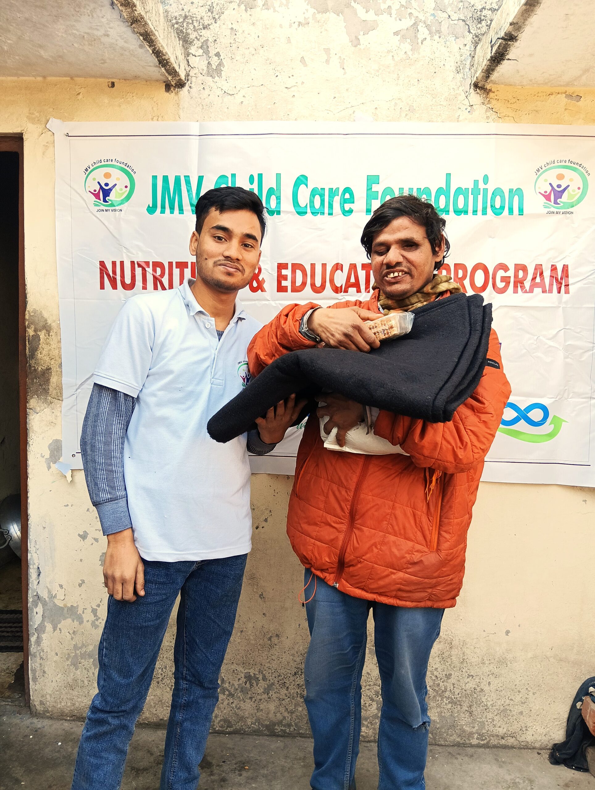 Supporter giving clothes and sweets to a visually impaired man, both appearing happy.”