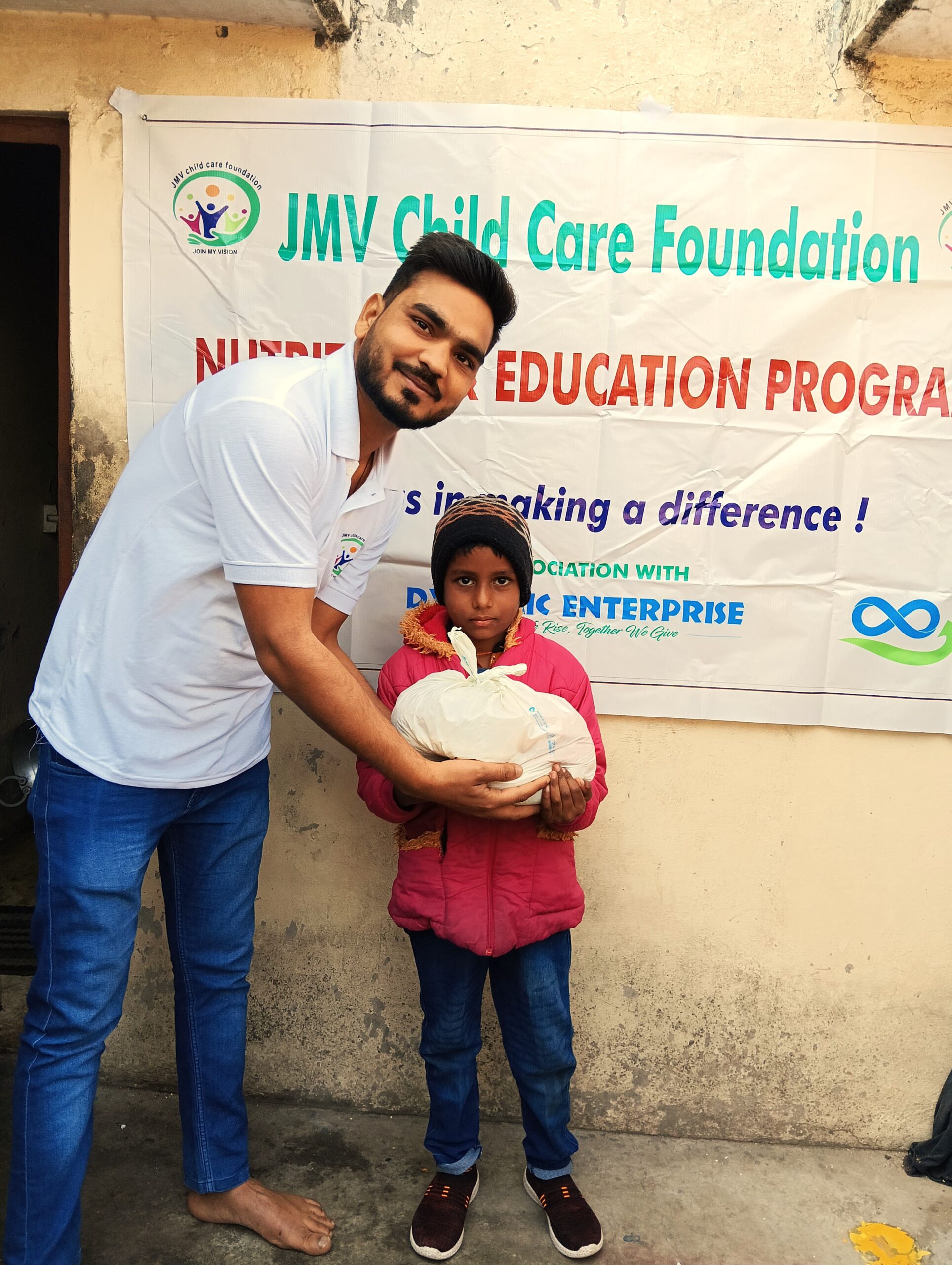 Supporter handing a wrapped present to a visually impaired Kid, who seem excited.